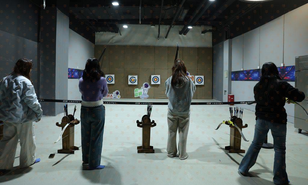数字运动馆模拟射击靶道区，多位顾客各自在靶位前持枪体验