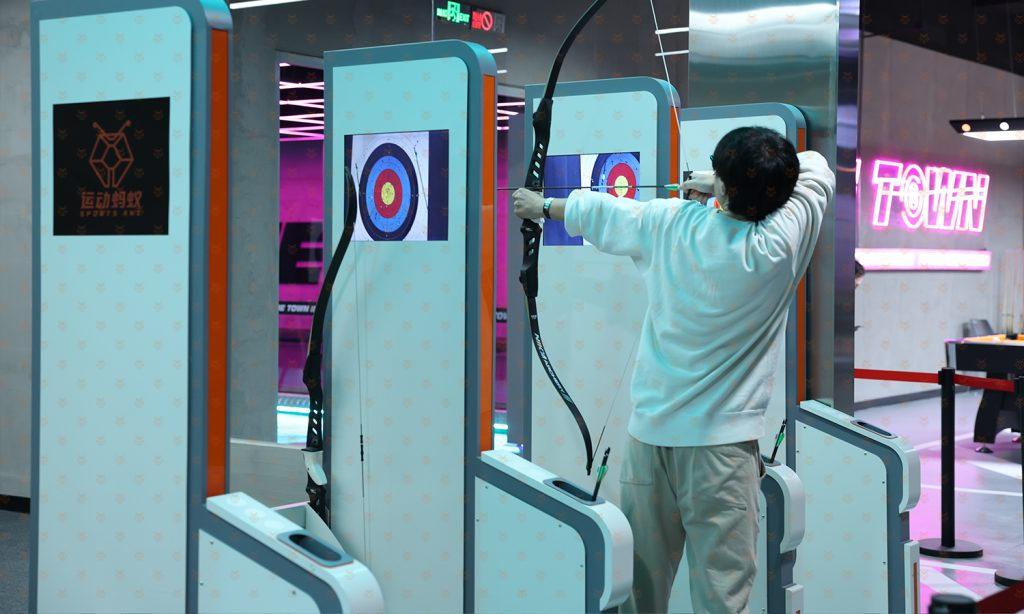 顾客在场馆内使用模拟射击设备,持枪对准独立电子靶位