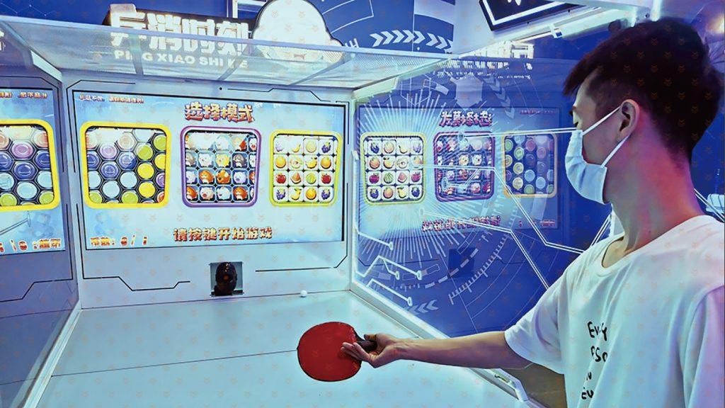 顾客手持感应球拍体验体感互动项目，屏幕显示实时比分