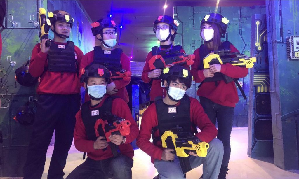 多名顾客佩戴防护装备分组合影，场馆团队活动与组队竞技氛围